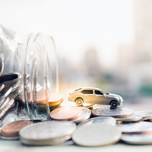 Autofinanzierung: Auto fährt über einen Münzstapel