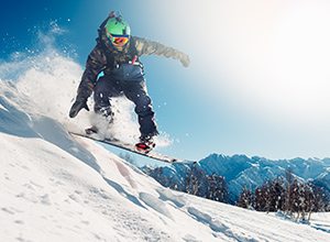 Wintersportversicherung: Snowboarder springt über Schanze
