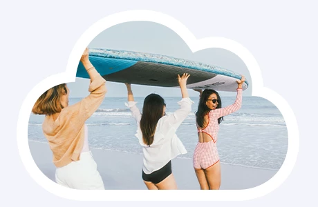 Drei Frauen, die am Strand ein Surfboard tragen.