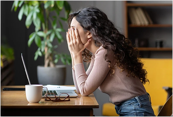 Frau sitzt verzweifelt vor geöffnetem Laptop.