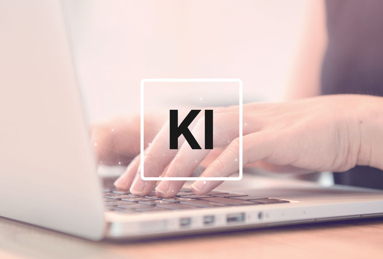 Hand, die auf Laptop tippt, darüber schwebend ein KI-Symbol