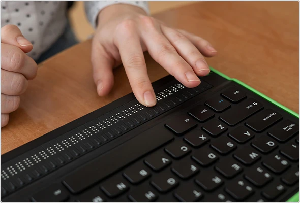 Ein Mensch nutzt eine in einer Tastatur integrierte Braillezeile.