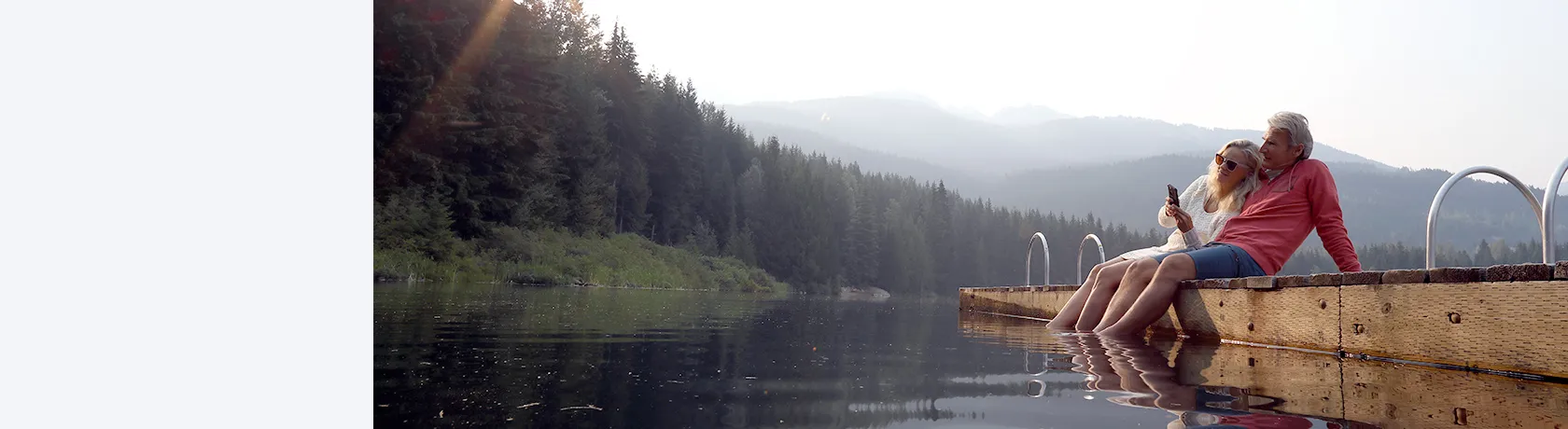 Paar mit Handy am See in den Bergen