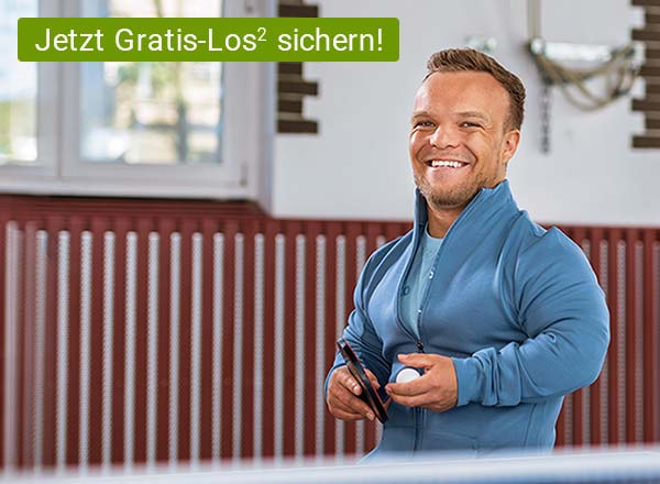 Lächelnder Mann in blauem Sportjacke hält Tischtennisschläger und Ball in einer Halle