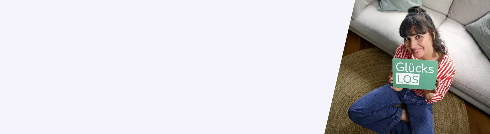 Frau mit rot-weiß gestreiftem Hemd hält rotes Smartphone vor sich, sitzt an Holztisch vor Bücherregal und Fenster mit Blick ins Grüne.