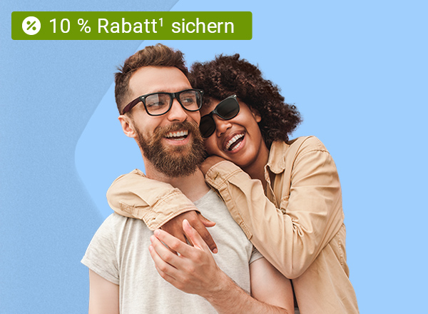 Ein Mann und eine Frau, welche beide lächeln und die Frau umarmt den Mann von Hinten seitlich. Der Mann trägt eine Brille mit einem schwarzen Rahmen und die Frau trägt eine schwarze Sonnenbrille.