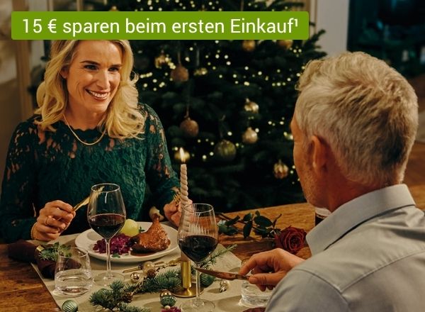 Zwei Personen feiern fröhlich beim Weihnachtsessen mit Wein und festlich gedecktem Tisch.