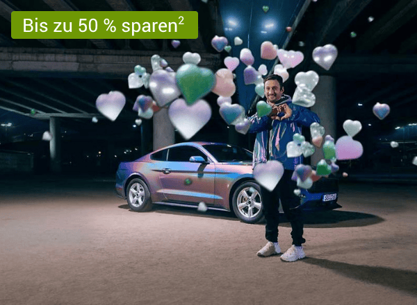 Mann steht neben silbernem Auto, umgeben von schwebenden Herz- und Sternsymbolen in verschiedenen Farben mit einem Text links oben der "+15 € Amazon.de Gutschein¹" lautet
