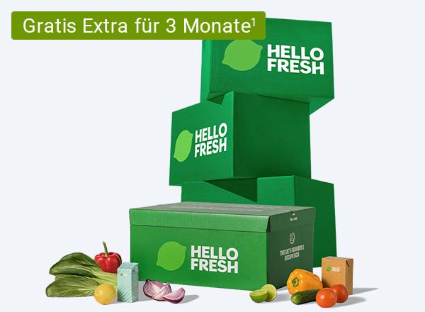 Drei grüne HelloFresh-Lieferboxen gestapelt mit einer weiteren Box im Vordergrund, daneben frisches Gemüse und Obst. Mit Chiptext: Gratis Extra für 3 Monate