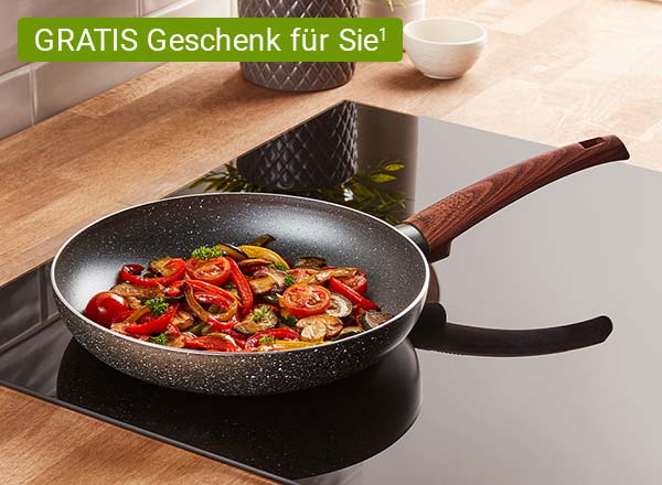 Bratpfanne mit Holzgriff auf Herd, gefüllt mit gebratenem Gemüse wie Tomaten, Paprika und Pilzen, dazu ein Chip mit dem Text: GRATIS Geschenk für Sie¹