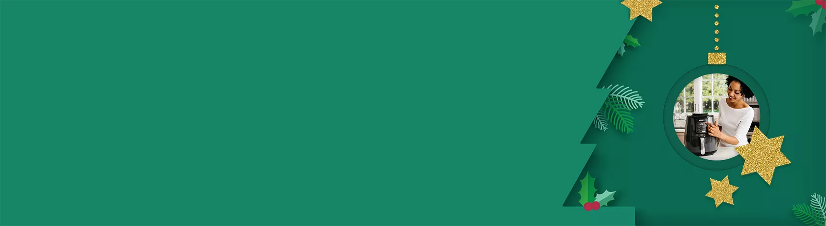 Frau in weißem Oberteil steht in moderner Küche vor schwarzer Heißluftfritteuse und hält Teller mit frittiertem Essen und Dip-Schale.