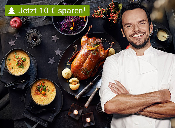 Festtagsmenü mit einer Ente lieght auf einem weihnachtlich dekorierten Tisch mit Steffen Henssler davor– Jetzt 10 € sparen!
