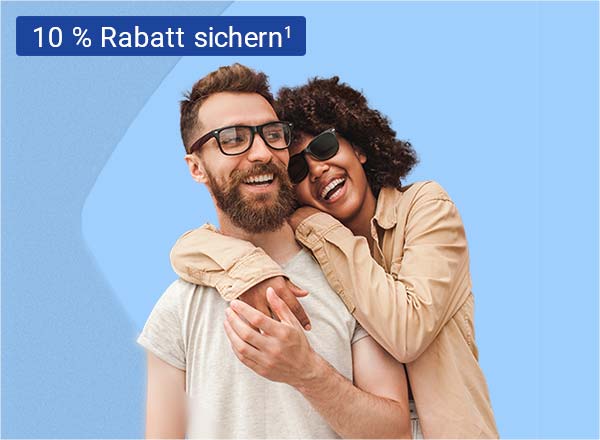 Ein Mann und eine Frau, welche beide lächeln und die Frau umarmt den Mann von Hinten seitlich. Der Mann trägt eine Brille mit einem schwarzen Rahmen und die Frau trägt eine schwarze Sonnenbrille.