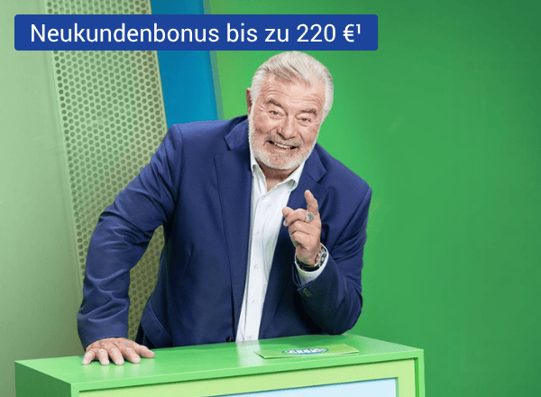 Älterer Mann im dunkelblauen Anzug stützt sich lachend auf grünes Pult und zeigt mit dem Zeigefinger auf sein Gegenüber.