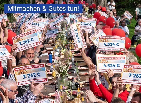 Menschen feiern mit Gewinnschecks an langer Tafel.