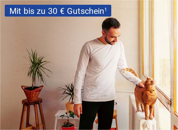 Ein Mann streichelt eine Katze, die auf einer Heizung steht. Im Hintergrund sind die Umrisse eines Wohnzimmers erkennbar.
