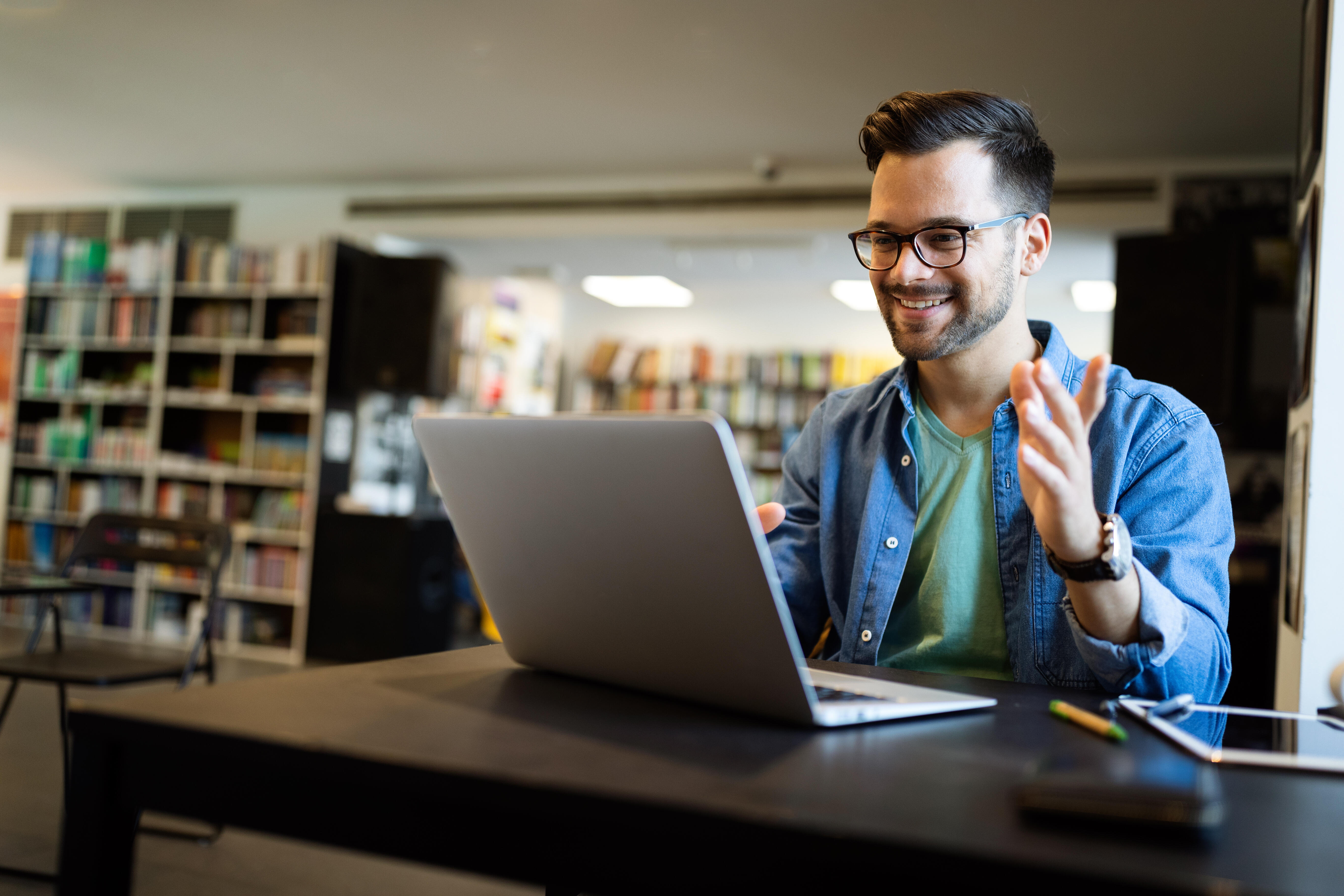 Smiling man using laptop in library