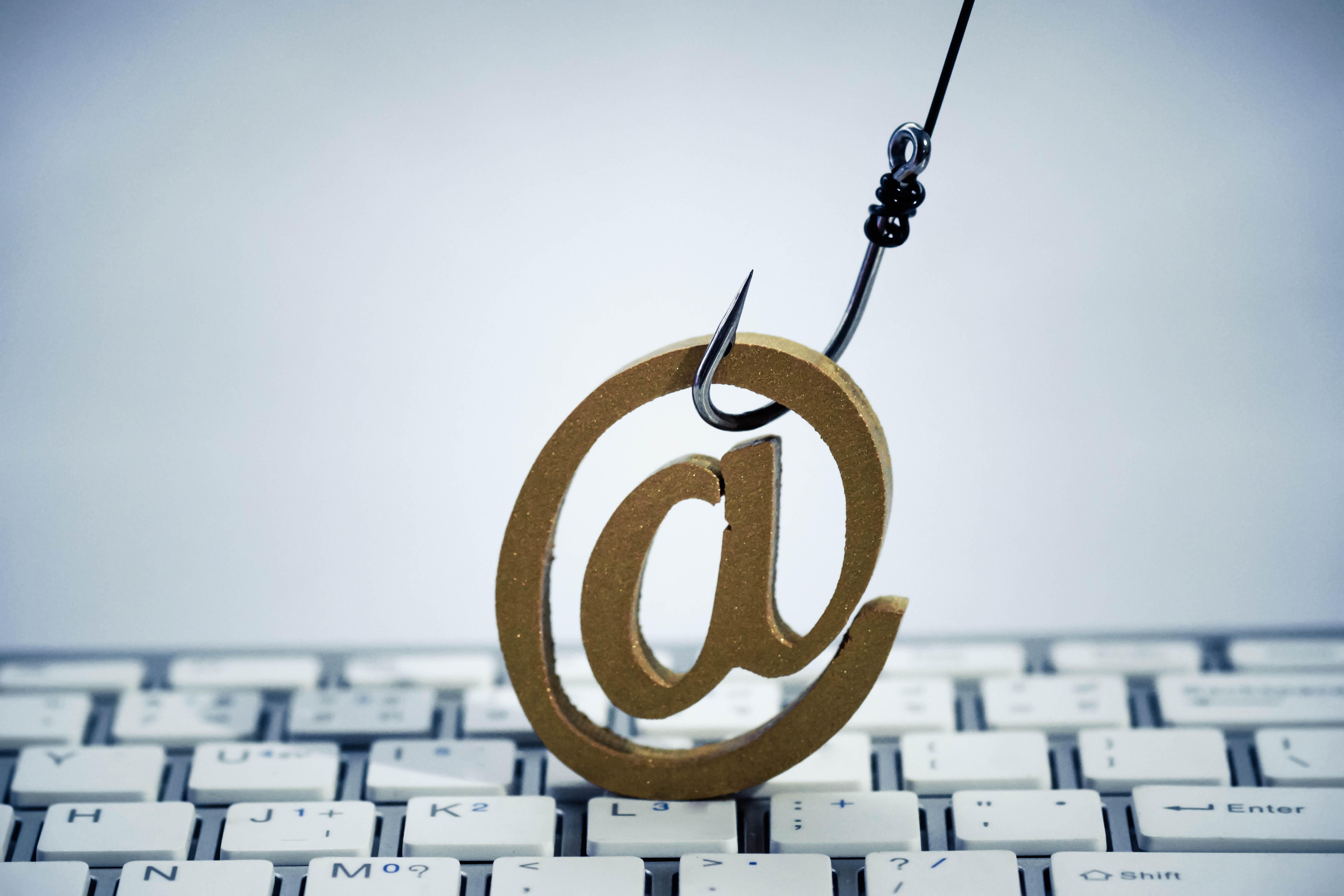 Image of fishhook hooking an @ symbol above a white computer keyboard