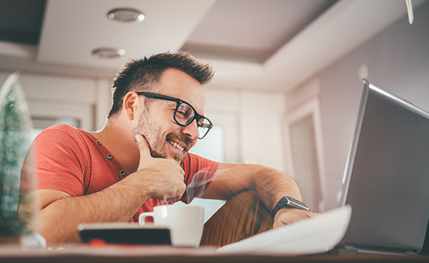 Smiling man reading email on laptop