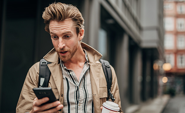 Man holding smartphone with shocked expression