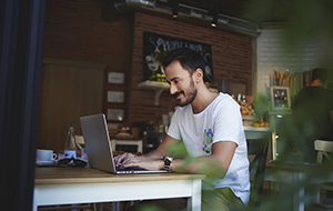 Young man working at computer in cafe