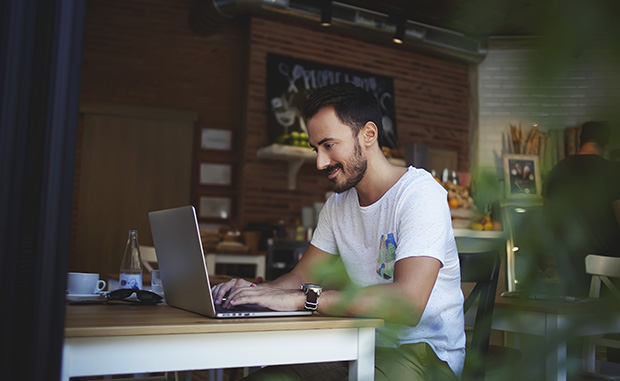 Young man working at computer in cafe