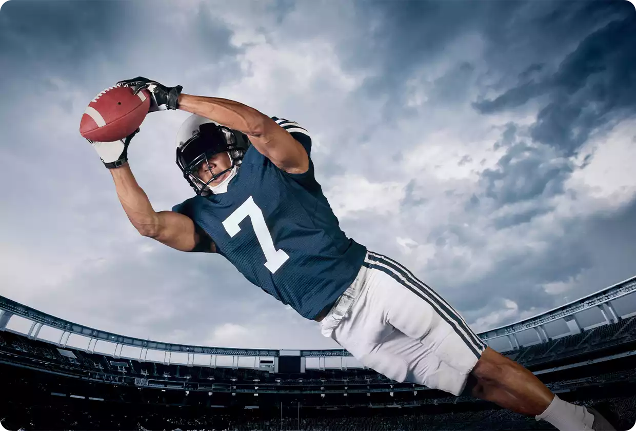 Football player dives to catch a ball in a stadium
