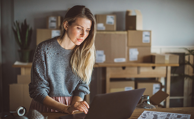 Working woman at online shop wearing casual clothing and using laptop for work organization