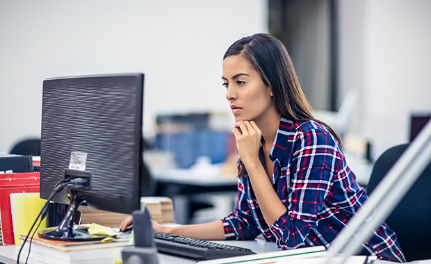 Young businesswoman sitting at her desk and working on computer in office