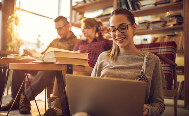 Smiling young women sits on floor looking at laptop