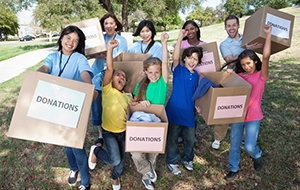 Group of smiling children and adults holding donation boxes