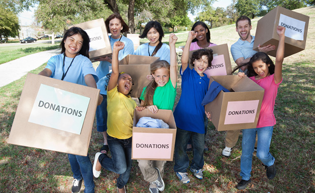 Group of smiling children and adults holding donation boxes
