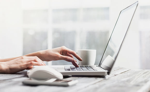 Place of work with hands on laptop keyboard