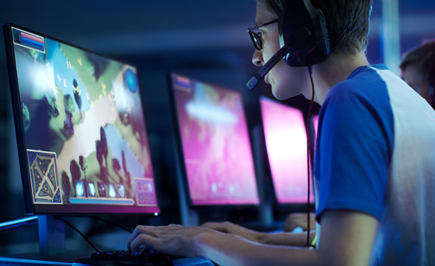 A man wearing a headset playing a game on his computer