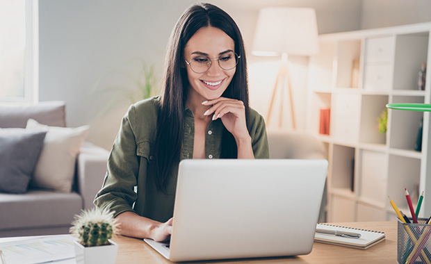 Smiling woman reads emails on laptop