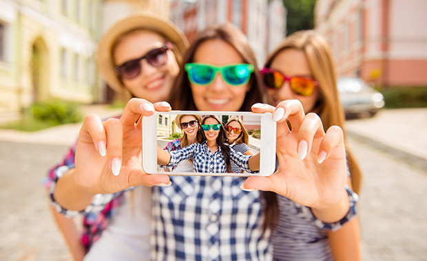 Three young women showing selfie on smartphone