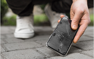 Hand picking up dropped smartphone with cracked screen