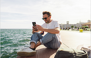Smiling middle-aged man sitting on a pier next to his backpack