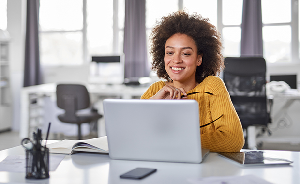 Smiling woman works on laptop in office