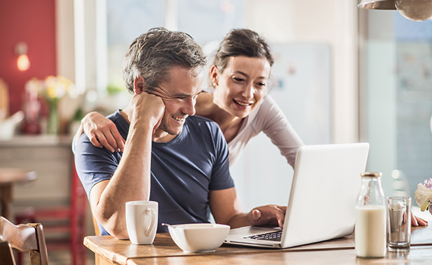 Man and woman in kitchen looking at laptop