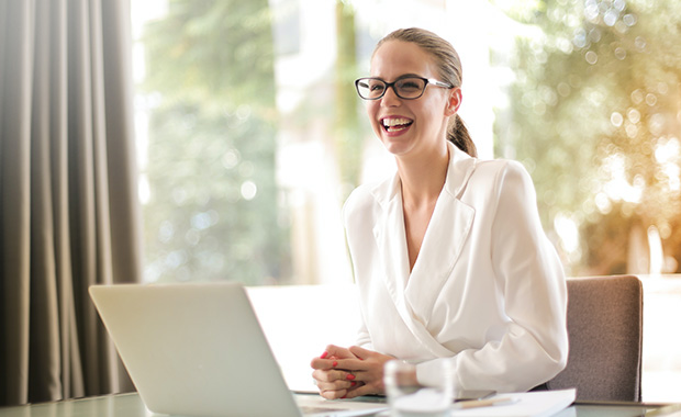 Young businesswoman working at laptop with pleased expression