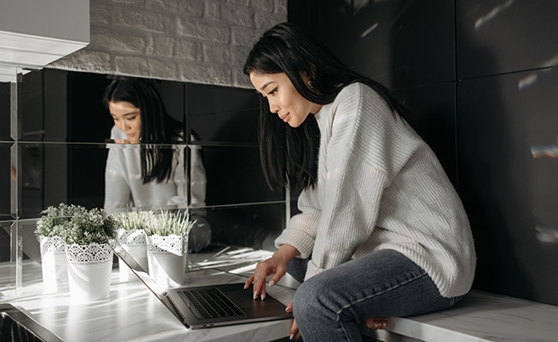 Woman in dark cafe reading email on laptop