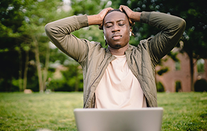 Man with laptop raising hands to head in frustration