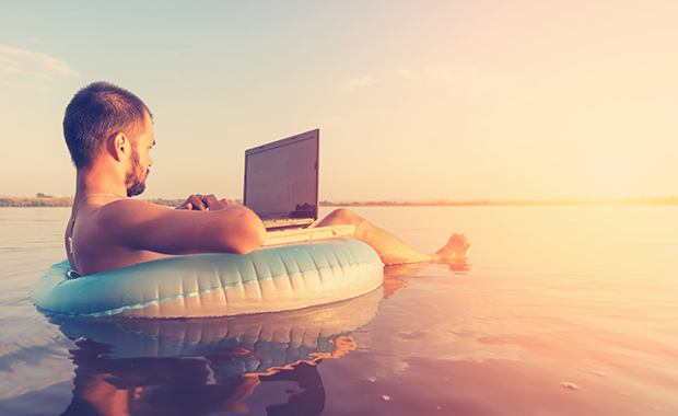 Man floats in innertube using laptop