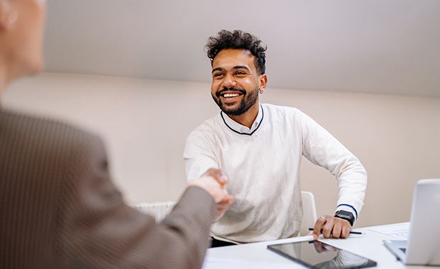 Smiling man shakes hands with unseen person