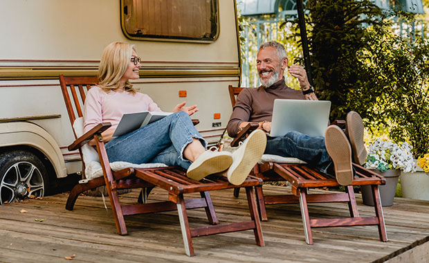 Smiling man and woman sitting outside caravan