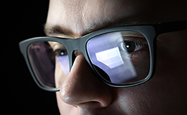 Closeup of man’s face with document reflected in eyeglasses