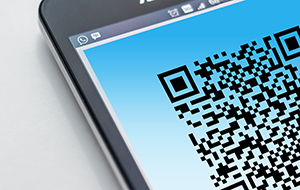 Corner of mobile device with screen displaying part of a QR code