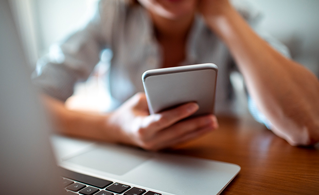 Hand holding smartphone next to laptop keyboard