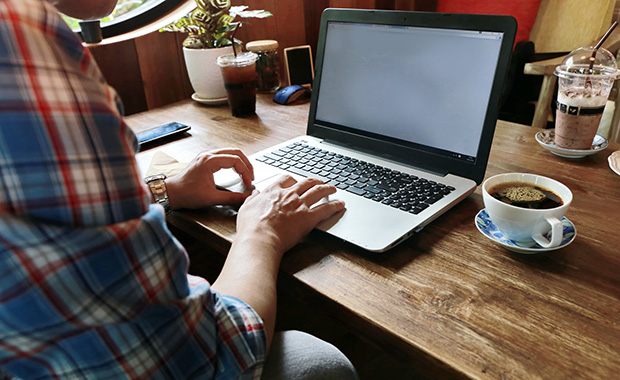 Open laptop on wooden desk with hands typing